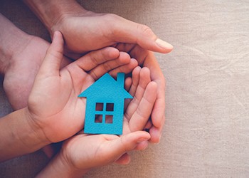 PHOTO: Adult and child hands holding cutout representing a home.