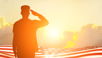Veteran saluting, American flag in background, at sunset