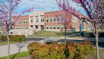 Front and right side of Howard Office Building seen from a distance through redbud trees 