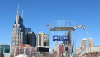 Metro Water Services branded glass pitcher filled with water at foreground of Nashville skyline