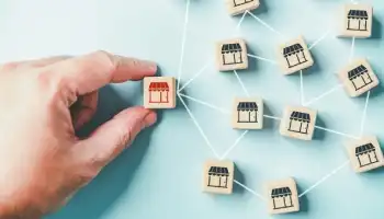 a hand holding a wooden block with a storefront on it connected to other wooden blocks