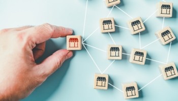 a hand holding a wooden block with a storefront on it connected to other wooden blocks