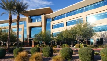 a large office building with palm trees and shrubs
