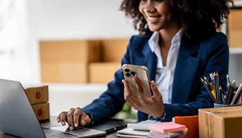 person working on laptop computer holding a cell phone