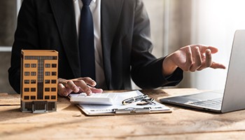 person working at computer with model of apartment building on desk