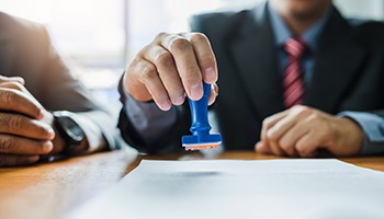 businessperson stamping a paper on a desk