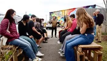 Photo of a group of people sitting in on a makeshift parklet learning about the program