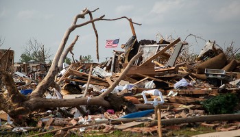 an American flag flies above tornado damage debris