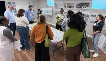 a group of people around a table reviewing plans at a meeting