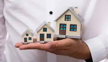 hand holding house models of different sizes
