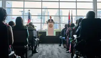 Mayor Freddie O'Connell delivers address to seated audience in modern conference room with large windows