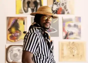 A man standing in front of a wall covered in artwork