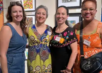 Four female artists standing side by side in front of art on display in Centennial Art Center. Left to right, Rhiannon Guppy, Pegah Kadivar, Martha Morales Purucker, Nadine Shillingford