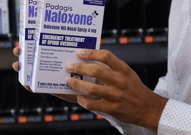 Close up photo of a person holing two boxes of Naloxone