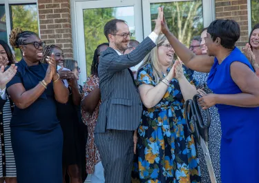 Group of people in formal attire clapping and celebrating at an outdoor event.