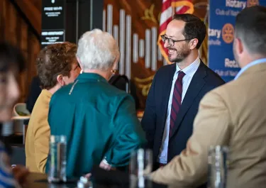 Business professionals networking at an indoor event, wearing business attire and name badges.