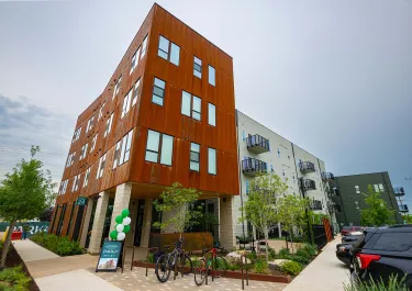 Orange brick residential building with modern architecture and ground-level commercial space in an urban neighborhood.