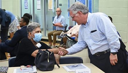 Mayor Cooper shakes the hand of a person sitting in a chair