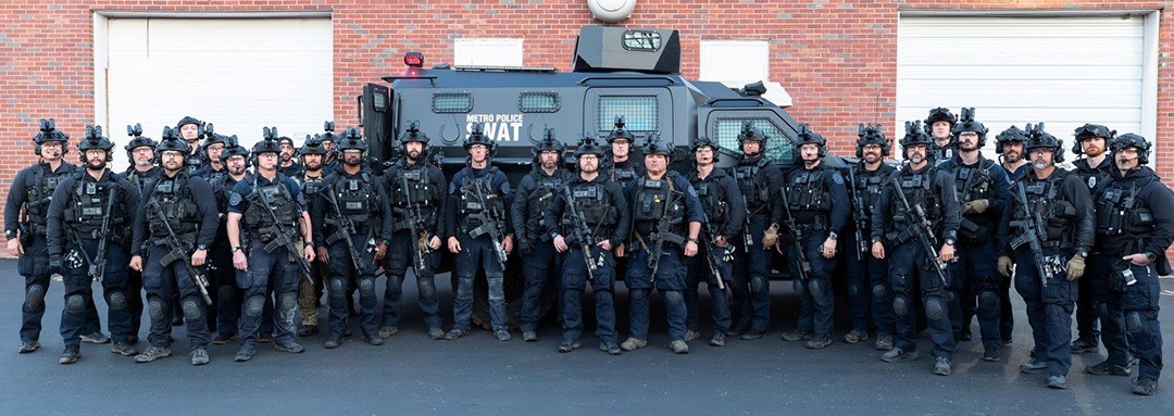 SWAT members in uniform in front of SWAT vehicle