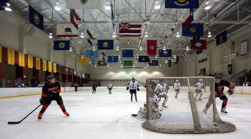 Two teams competing in Ice Hockey on an indoor rink