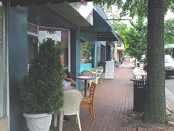 Photo of a brick sidewalk with shrubs and patio tables