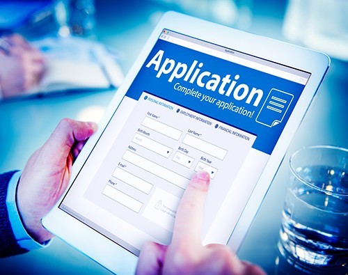 photo of hands holding digital tablet displaying an application form