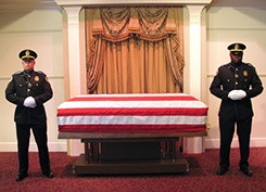 Photo of two Metro Police officers standing beside a coffin draped in American flag