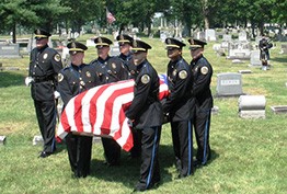 Metro Police officers carrying a flag draped coffin at a cemetery