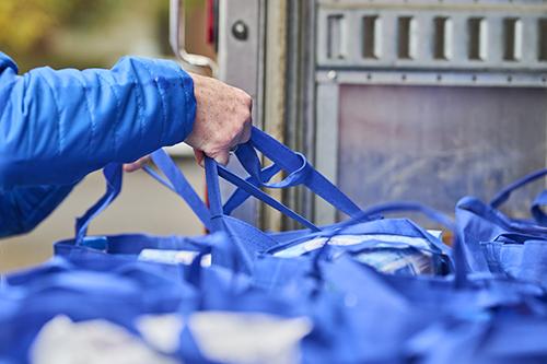 Photo of person picking up grocery bags