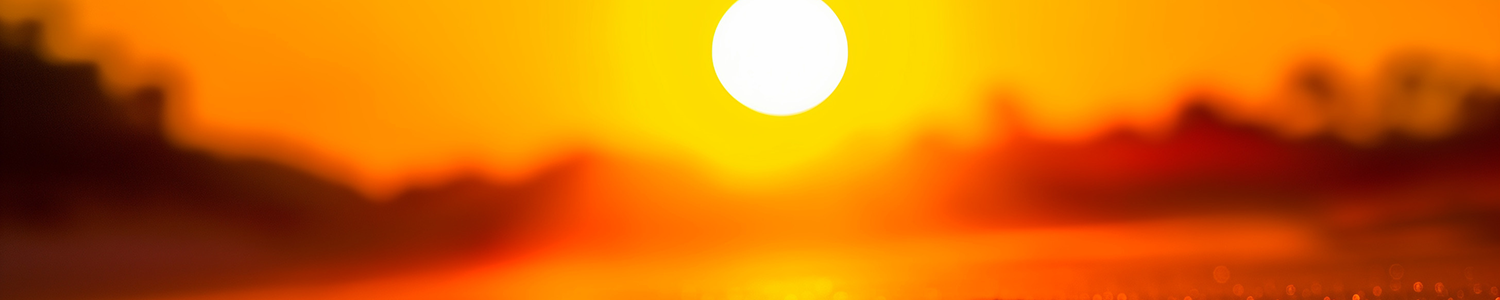 Golden sunset over a dark landscape with the sun glowing brightly on the horizon.