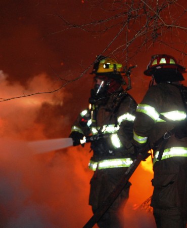 firefighters putting out fire with hose