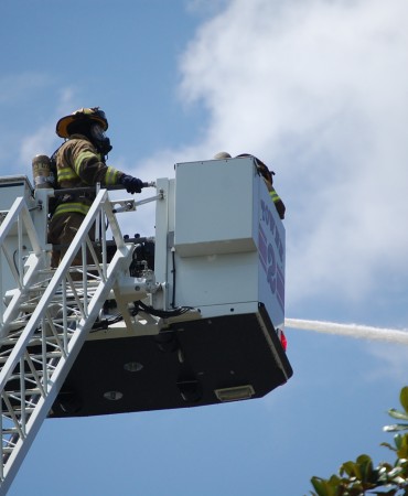firefighter in bucket truck using hose
