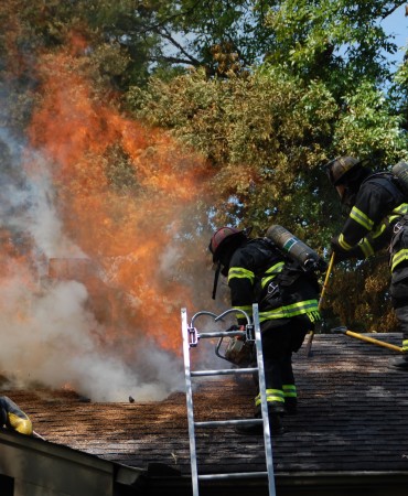 firefighters on roof of house fire