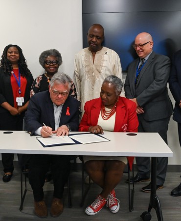 Mayor John Cooper signs International Pledge to fight HIV/AIDS with other attendees in background
