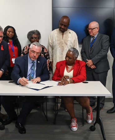 Dr. Jose M. Zuniga signs international pledge to fight HIV/AIDS with others in background