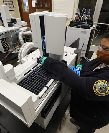 Scientist loading evidence samples (extracts) on the GC/MS (Gas Chromatograph/Mass Spectrometer) to be analyzed for the presence of controlled substances