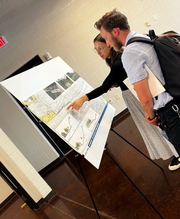 two people looking at plan, one pointing at a specific part of the plan diagram