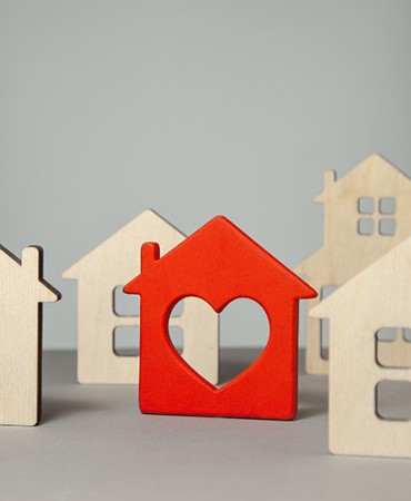 a group of small wooden house tiles including one red tile with a heart