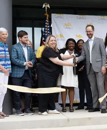 ribbon cutting ceremony at the Strobel House grand opening ceremony with several people on stage including Mayor Freddie O'Connell