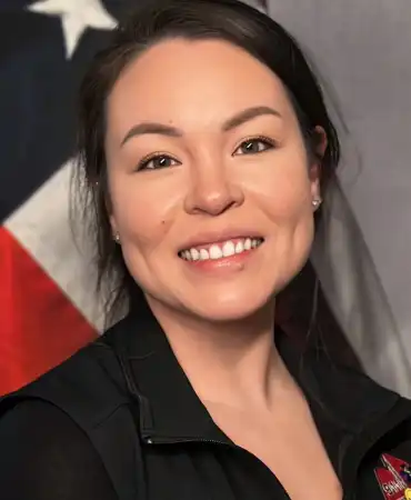 woman poses for a professional headshot in front of american flag