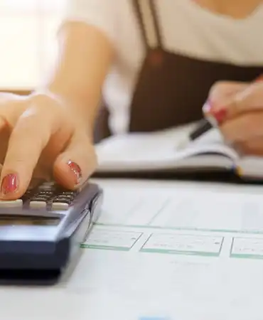 person taking notes and using a calculator