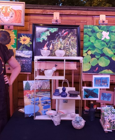 Teacher and Gallery Manager, Amy Sterling, posed alongside her artwork for sale in the artist garden