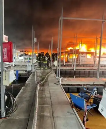firefighters working a boat fire on a marina dock