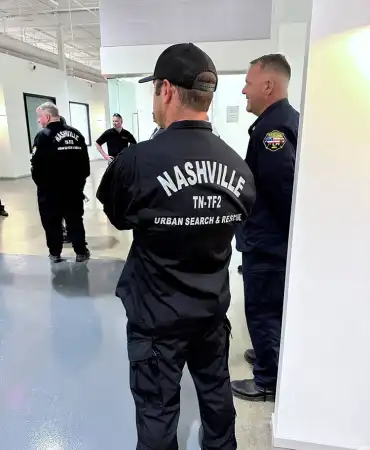 Police officers in training room wearing black uniforms and tactical gear during indoor instruction.