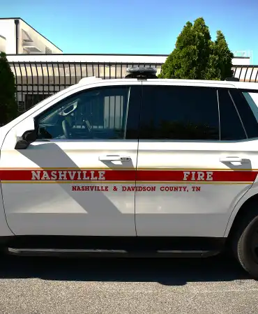 White emergency response vehicle with red and blue striping parked outdoors.