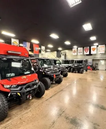 Red all-terrain utility vehicle displayed in spacious warehouse showroom with polished concrete floor.
