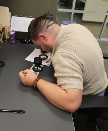 Scientist performing manual comparisons utilizing a fingerprint magnifier and ridge counter tools