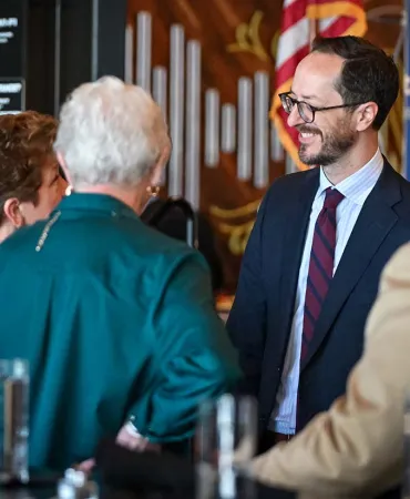 Mayor networking at an indoor event, wearing business attire and name badges.