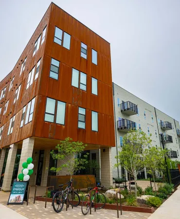 Orange brick residential building with modern architecture and ground-level commercial space in an urban neighborhood.