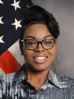 Woman wearing glasses smiling in front of American flag